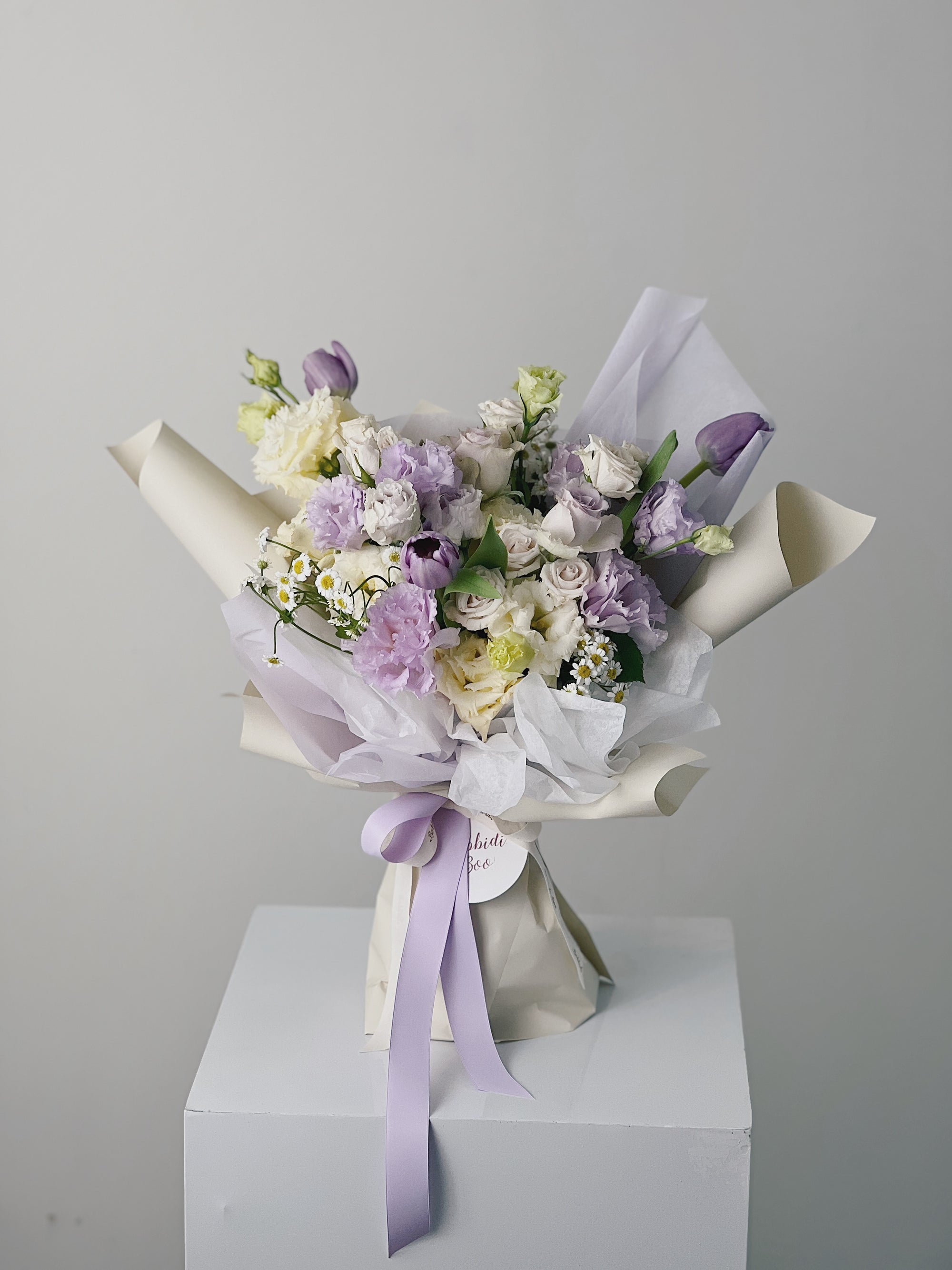 紫色和白色鮮花花束,包裝有紫色絲帶。