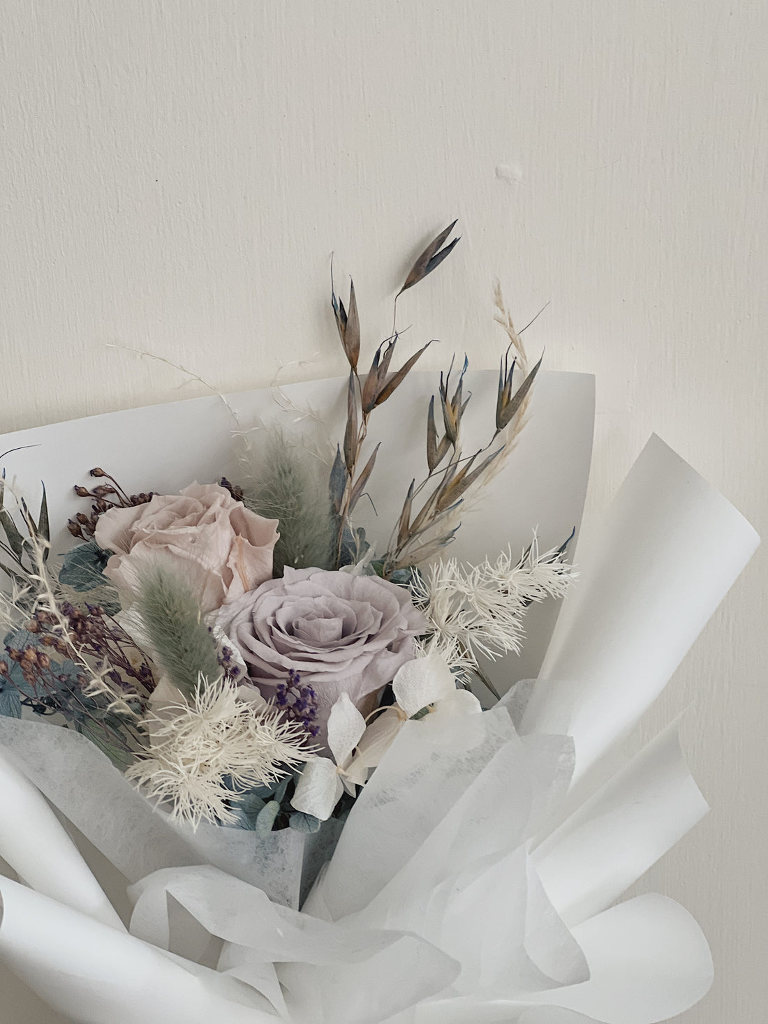 一束永生玫瑰花,包裹精美白色花紙。