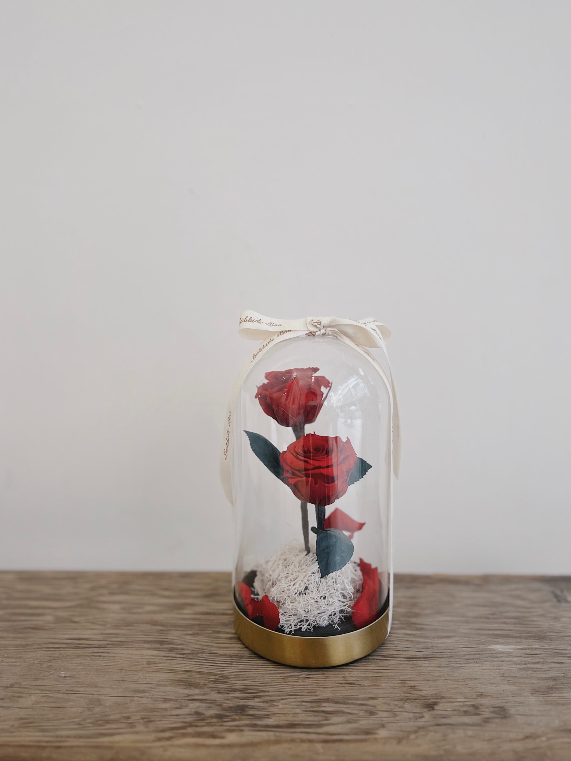 玻璃罩內有兩朵紅色永生玫瑰,底座上有苔蘚裝飾。