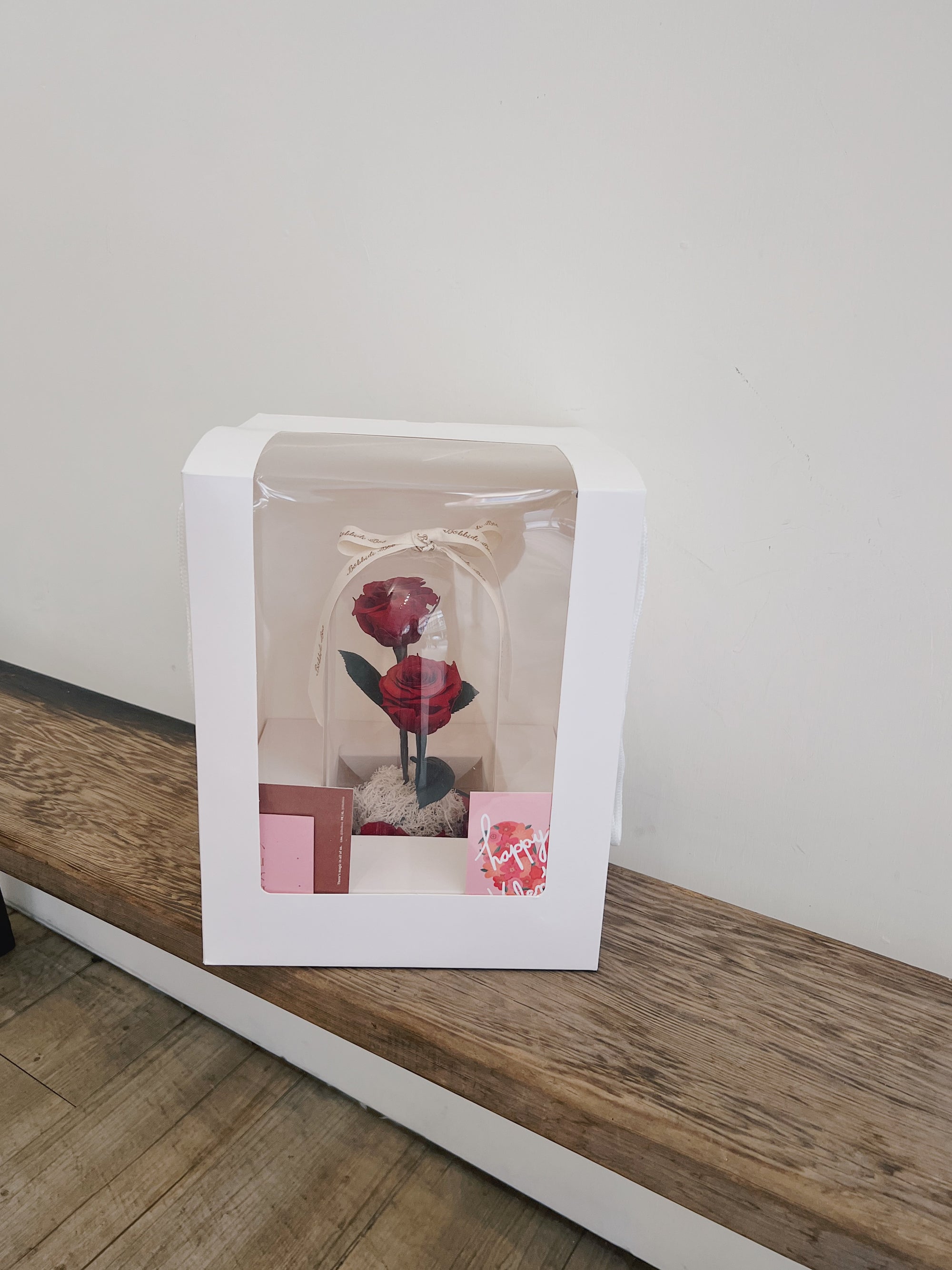 白色盒裝的紅色永生玫瑰,置於玻璃罩內。