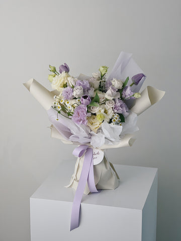 紫色和白色花束,包裝精美,綁有紫色絲帶。