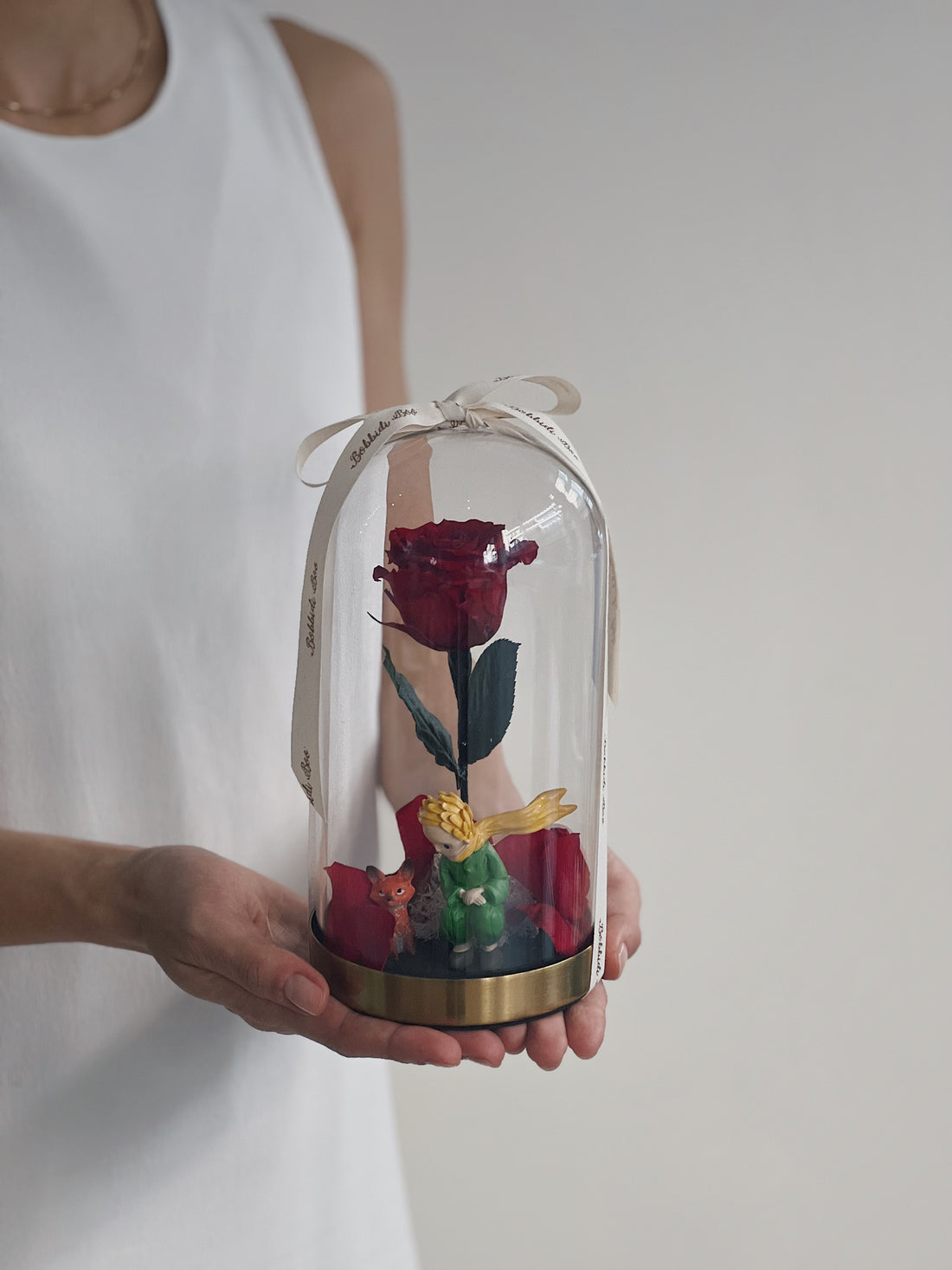 紅玫瑰在玻璃罩內,小王子與狐狸雕像在旁。