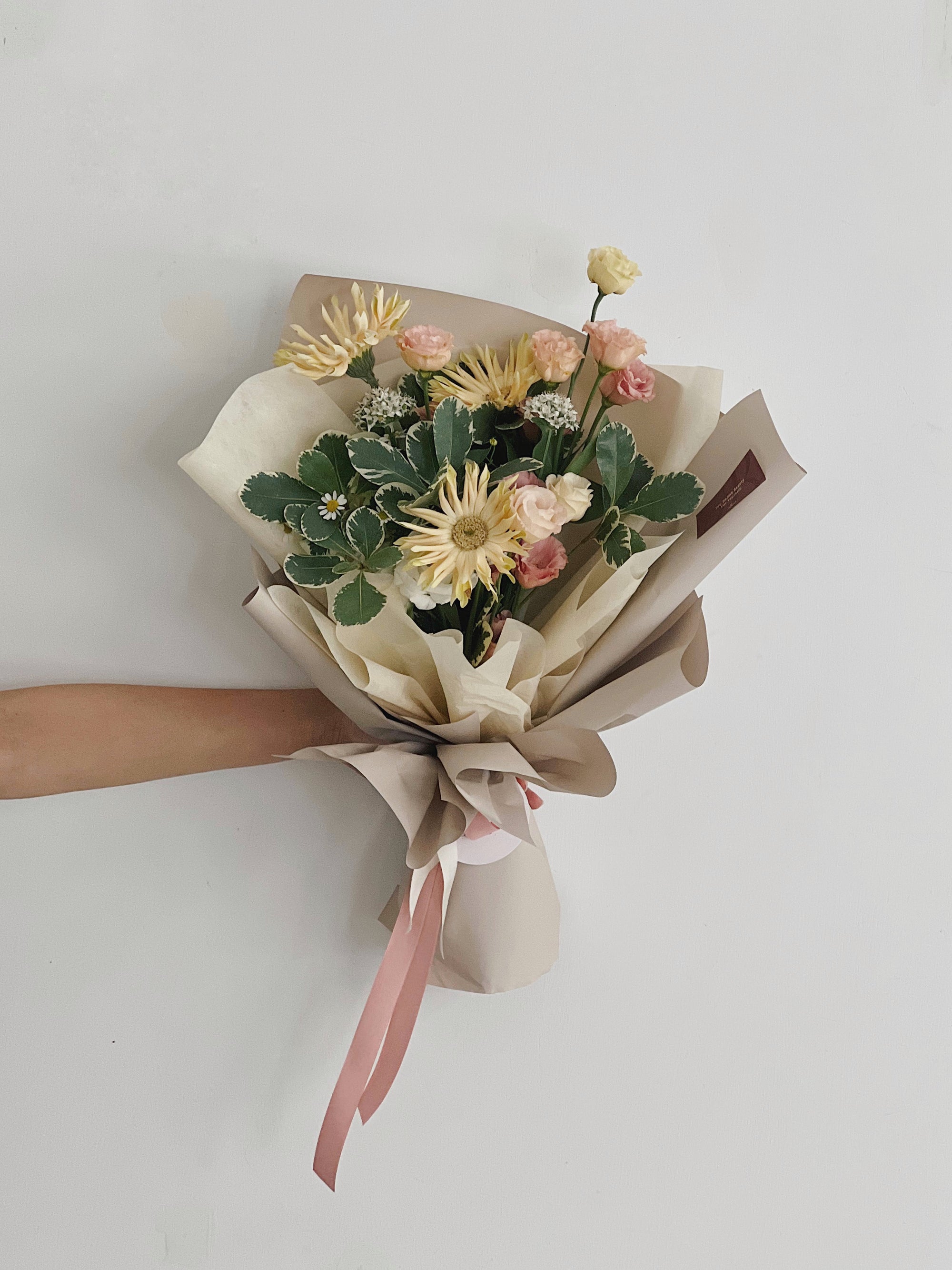 一束含太陽花和康乃馨的花束，包裝簡約。
