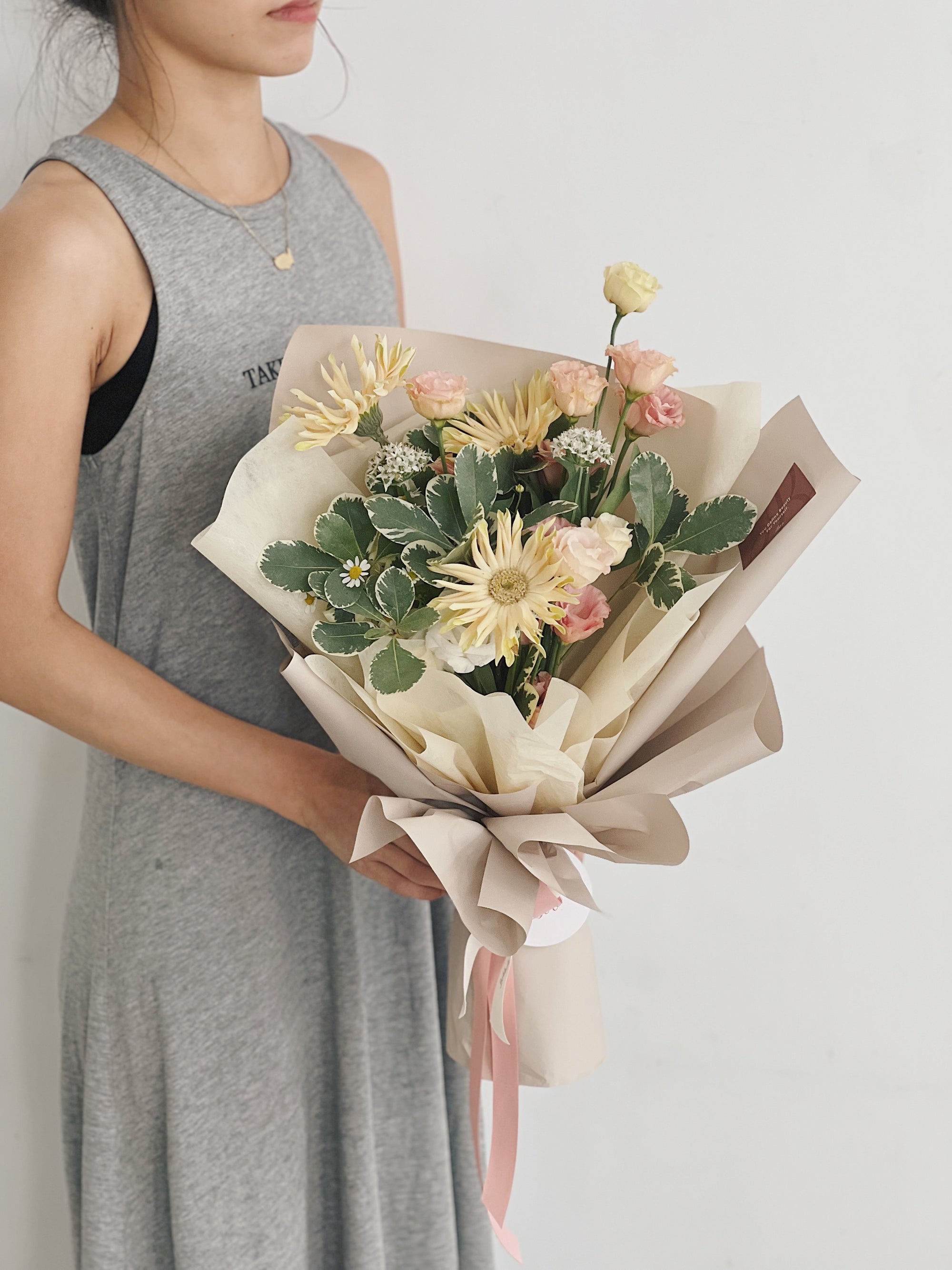 女人手持太陽花與淡色花卉的花束。