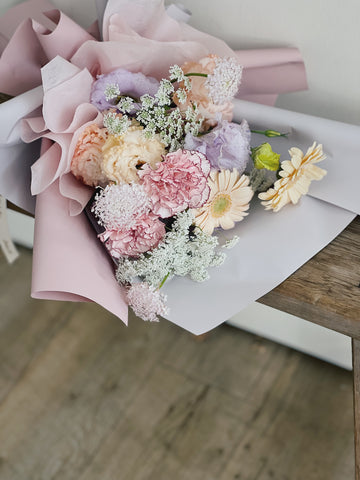 粉嫩色系鮮花花束，包含康乃馨和雛菊。