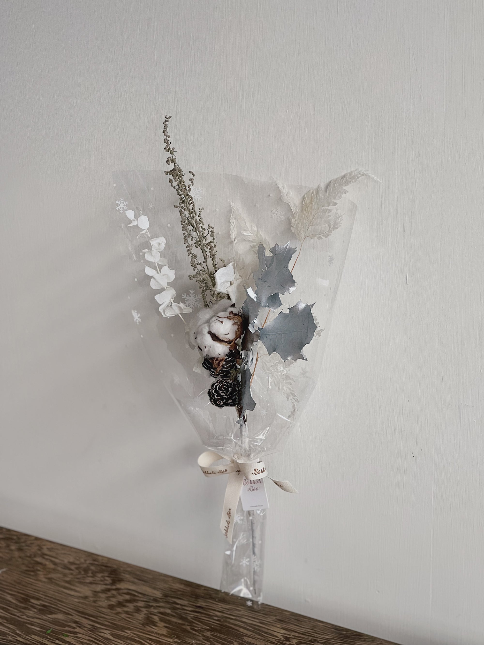 透明包裝的乾燥花束,包含棉花與其他白色和深色乾燥植物。