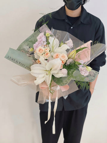 穿黑衣的人手持百合花束，鮮花用綠色包裝。