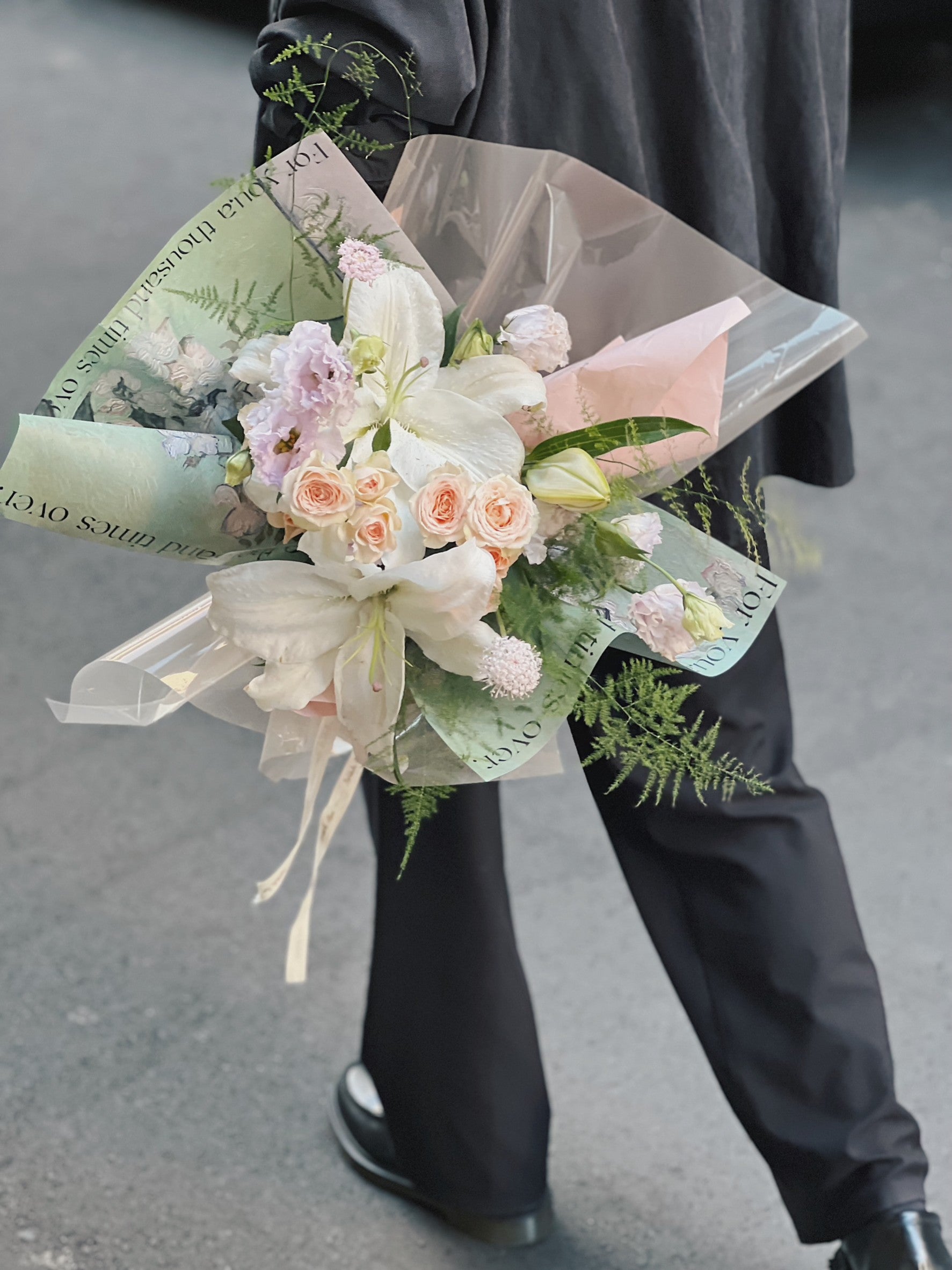 綠色包裝的百合花花束，包含白色百合和粉色玫瑰。